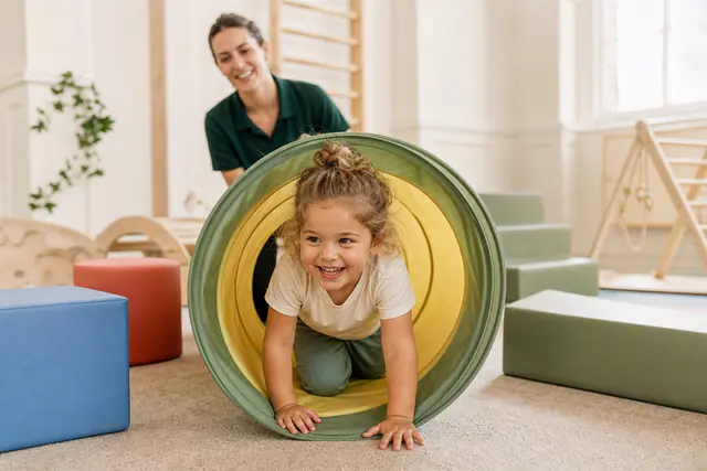 A child crawling through a soft movement tunnel